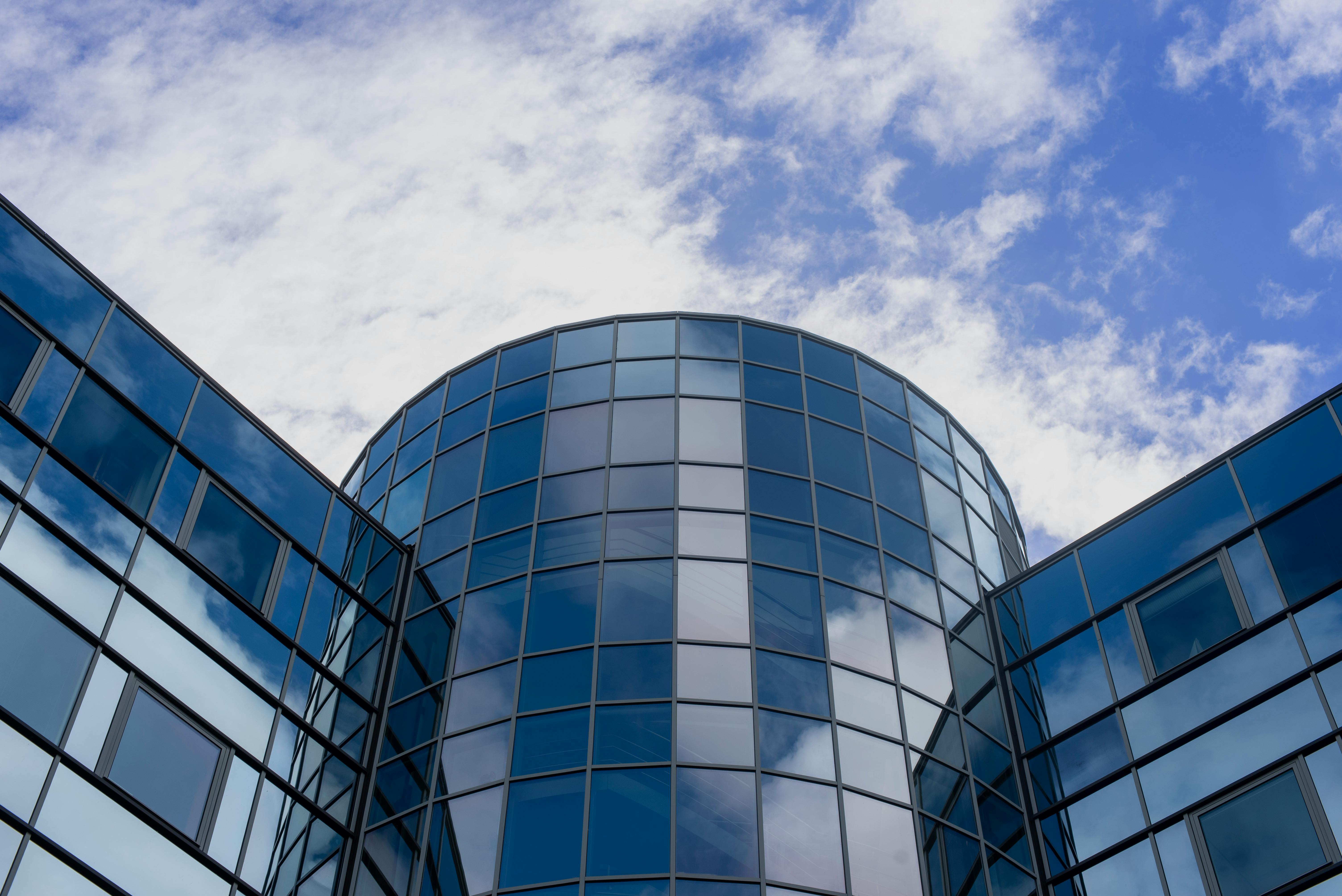 Modern corporate office building exterior — glass and steel architecture, city backdrop