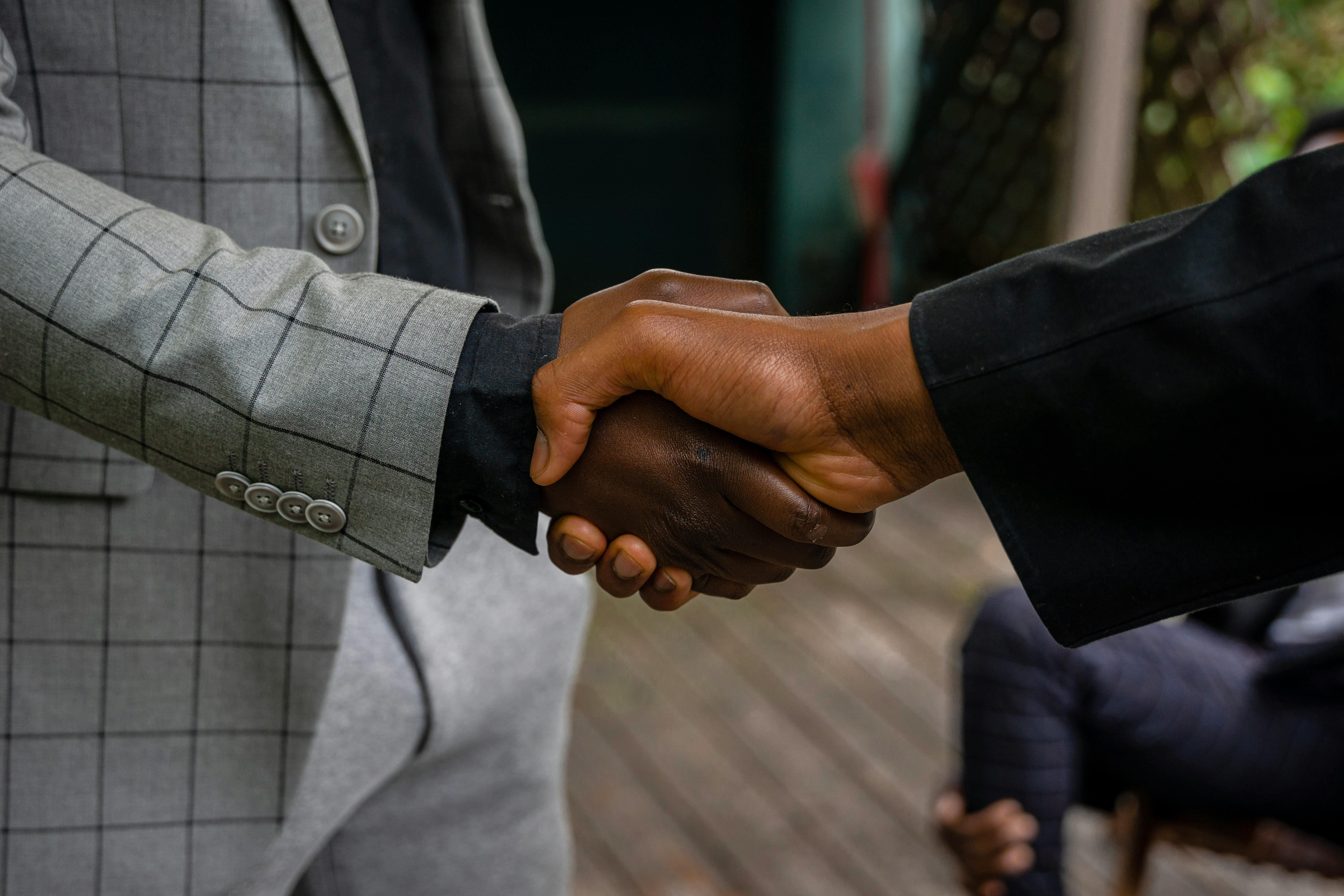Business partnership meeting — executives shaking hands, corporate boardroom