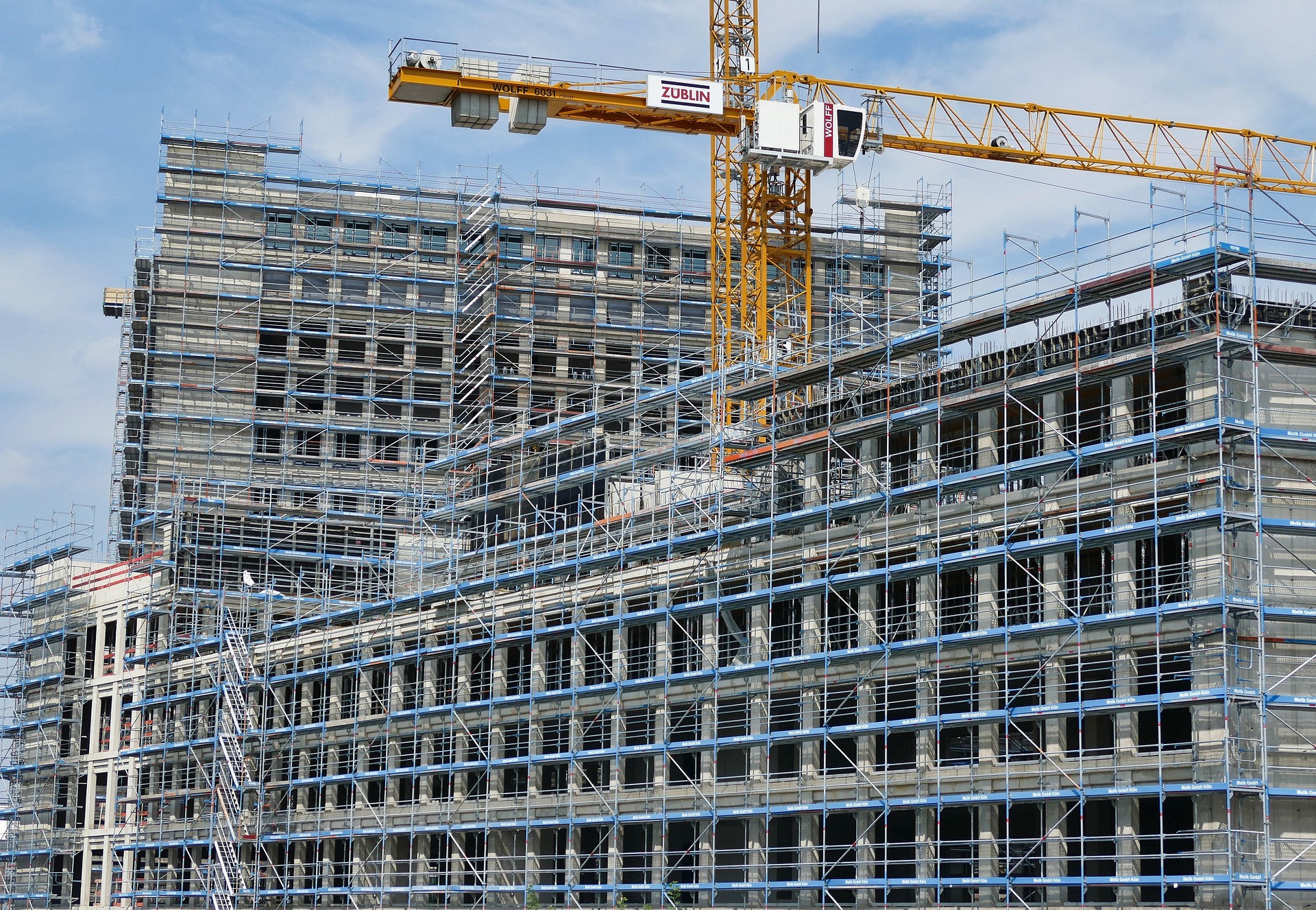 Large-scale construction and infrastructure development project — cranes, scaffolding, and modern commercial building under construction